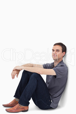 Close-up of a dark brown hair man sitting against a wall