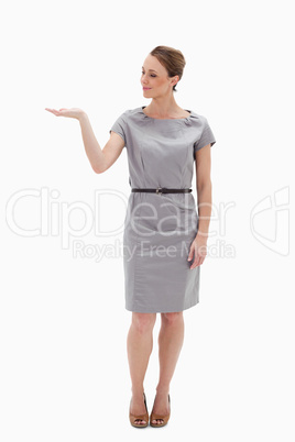 Woman in a dress presenting something with her hand