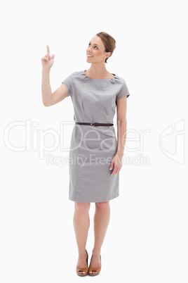 Smiling woman in dress showing something above with her hand