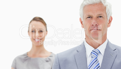 Close-up of a serious white hair businessman with a woman smilin