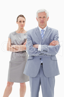 Serious white hair businessman with a woman behind him crossing