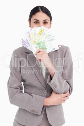 Young businesswoman hiding her face behind bank notes Young businesswoman hiding her face behind bank notes