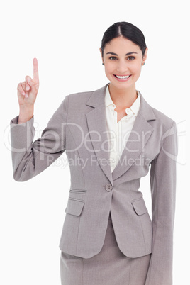Smiling young businesswoman pointing up