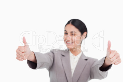 Thumbs up given by smiling young businesswoman