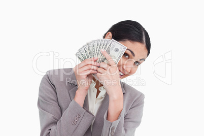 Young saleswoman covering her face with bank notes