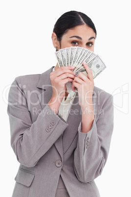 Young saleswoman hiding her face behind bank notes