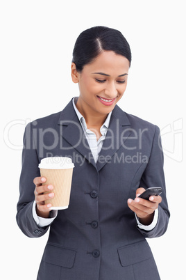 Close up of saleswoman with paper cup reading text message