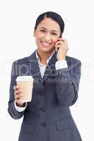 Close up of smiling saleswoman with paper cup and cellphone
