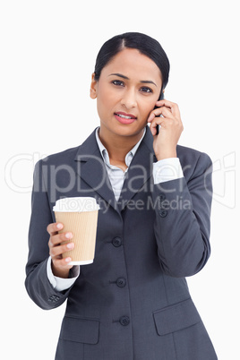 Close up of serious saleswoman with paper cup and cellphone