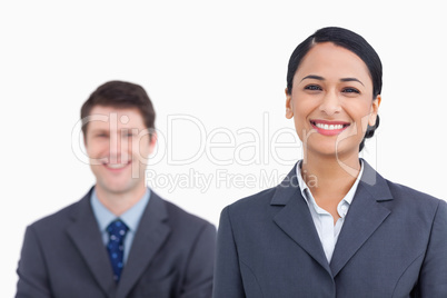 Close up of smiling saleswoman with colleague behind her Close up of smiling saleswoman with colleague behind her