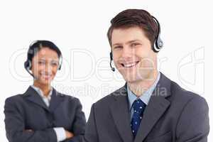 Close up of smiling male call center agent with colleague behind