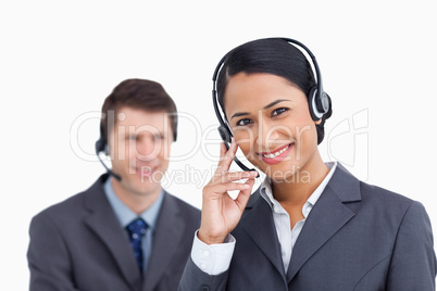 Close up of smiling call center agent with colleague behind her Close up of smiling call center agent with colleague behind her