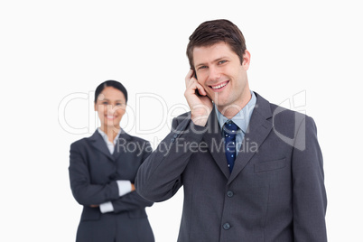 Close up of smiling salesman on the phone with colleague behind