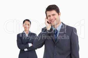 Close up of smiling salesman on the phone with colleague behind