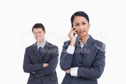 Close up of serious saleswoman on the phone with co-worker behin