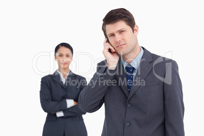 Close up of salesman on the phone with colleague behind him