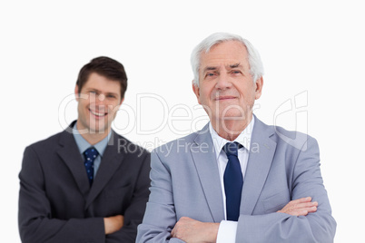 Close up of mature businessman with folded arms and colleague be