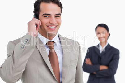 Salesman on his cellphone with colleague behind him