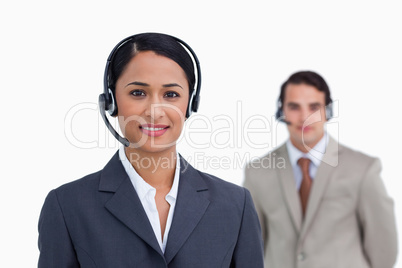 Smiling telephone support worker with colleague behind her