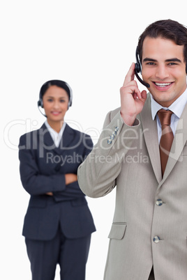 Smiling hotline employee with colleague behind him
