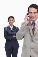 Smiling hotline employee with colleague behind him