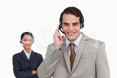 Smiling hotline employee with co-worker behind him