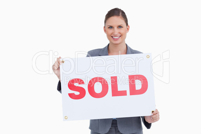 Smiling real estate agent presenting sold sign