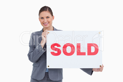 Smiling real estate agent holding sold sign