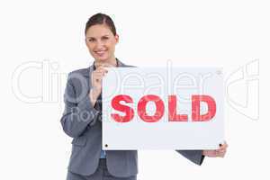 Smiling real estate agent holding sold sign