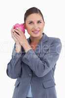 Smiling bank clerk shaking piggy bank