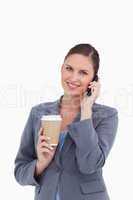 Smiling tradeswoman with paper cup on her cellphone