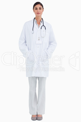 Serious looking female doctor with hands in her pockets