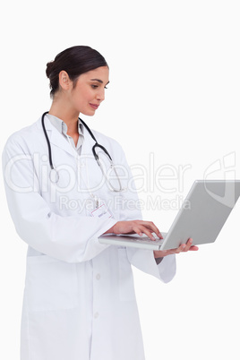 Side view of female doctor working on her laptop