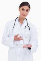 Female doctor pointing at pill in her hand