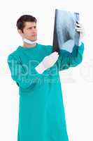Close up of male doctor wearing scrubs looking at x-ray