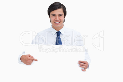 Smiling young tradesman pointing at blank sign in his hands