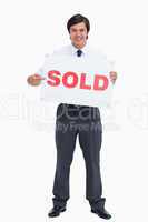 Smiling male real estate agent pointing at sold sign
