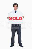 Smiling male real estate agent with sold sign