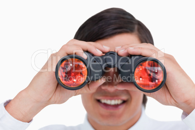 Close up of smiling young tradesman looking through binoculars