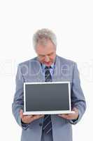 Mature tradesman holding and looking at laptop screen