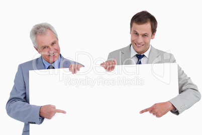 Smiling tradesmen pointing at blank sign in their hands