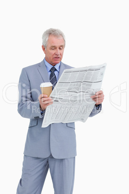 Mature tradesman with paper cup reading news paper