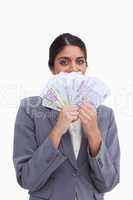 Female entrepreneur hiding her face behind bank notes