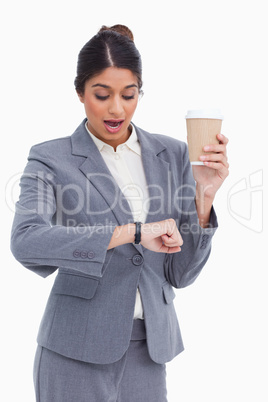 Shocked female entrepreneur with paper cup looking at her watch