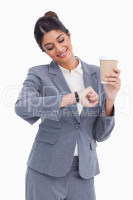 Smiling female entrepreneur with paper cup looking at her watch