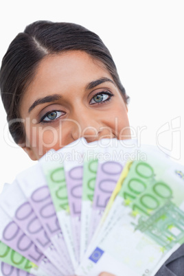 Close up of female entrepreneur hiding her face behind bank note