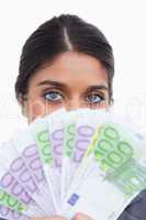 Close up of female entrepreneur hiding her face behind money