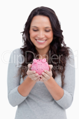 Smiling woman looking at piggy bank in her hands