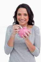 Smiling woman putting money into her piggy bank