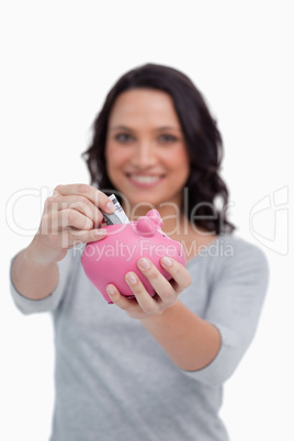 Money being put into piggy bank by woman